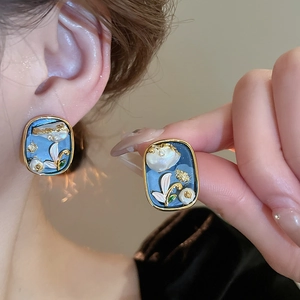 Macro detail of French vintage blue enamel floral stud earrings with pearls and gold foil