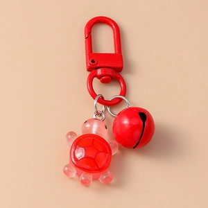 Close-up of red resin turtle pendant with matching bell and metal hook keychain
