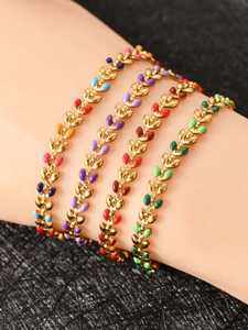 Macro shot of 18K gold olive leaf bracelets with colorful enamel inlay on a model wrist