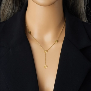 Detail einer vergoldeten Y-Halskette mit Gänseblümchen auf einem schwarzen Blazer