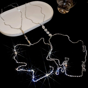 Macro view of crystal heart and teardrop body chains on luxury black background