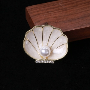 Detail of enamel shell brooch with a large central pearl and sparkling rhinestones