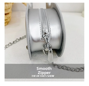 Detail of smooth silver metal zipper and chain strap on glossy dolphin bag for kids