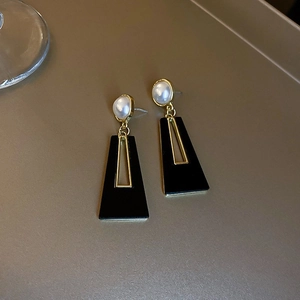 Close-up of geometric earrings with white pearls and black hollow rectangular pendants