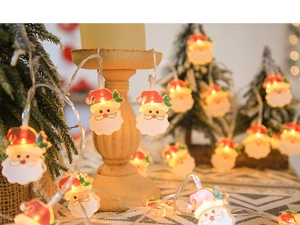 Close-up of glowing Santa Claus LED string lights wrapped around a festive candle holder