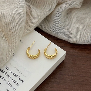 Detailed view of golden twisted hoop earrings on a vintage book page backdrop