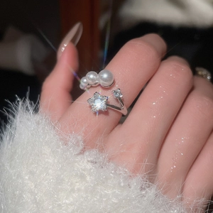 Detailed view of silver open ring with pearls and a sparkling star zircon on a finger