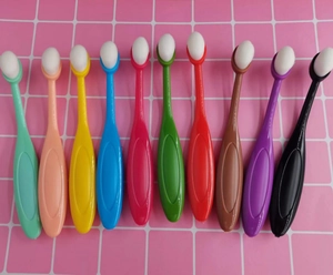 Set of ten colorful oval makeup brushes for concealer and lip application on pink grid background