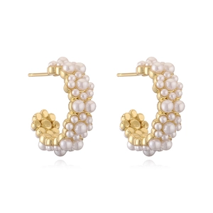 Detailed view of gold C-shaped hoop earrings featuring clustered white pearl embellishments