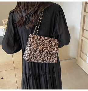 Detail shot of leopard print canvas shoulder bag with elegant gold chain strap worn by model