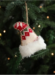 Close-up of a knit Christmas hat ornament with plush trim hanging on a tree