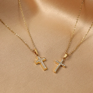 Detail of two gold cross necklaces with micro-set cubic zirconia on champagne silk fabric