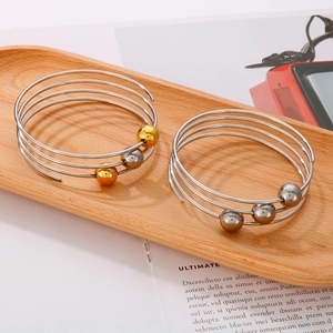 Minimalist multi-layer spiral stainless steel rings with silver and gold beads on a tray