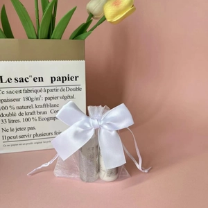 White organza drawstring gift bag with a satin bow and translucent mesh texture