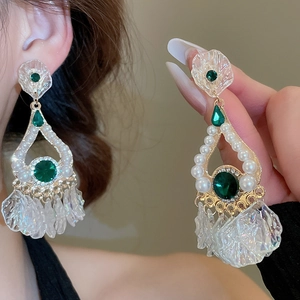 Detail of luxury drop earrings with green gemstones and shimmering leaf tassels