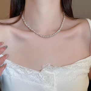 Close-up of elegant pearl necklace with sparkling rhinestones on model's neckline