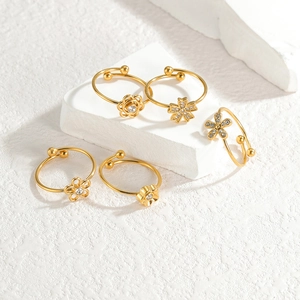 Detail of five adjustable gold rings with floral daisy patterns and zircon accents