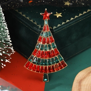 Macro detail of Christmas tree brooch with red and green crystals on green velvet
