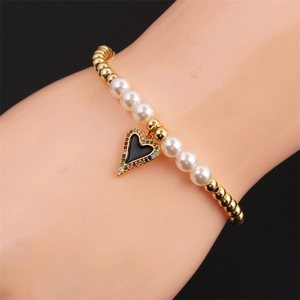Detail of beaded heart bracelet with gold metal beads, white pearls, and zircon charms