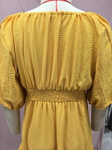 Detail of yellow textured midi dress with elastic waist and scalloped sleeve edges