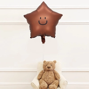Close-up of a brown star-shaped foil balloon with a smiley face and a teddy bear
