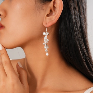Detail of silver floral drop earrings with a pearl accent worn on a model's ear