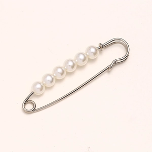 Macro shot of 7 white pearls on a gold metal waist pin for clothing adjustment