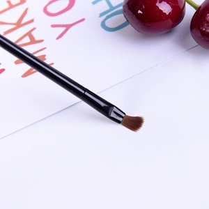 Detail of round silicone lip brush with black handle and brown bristles on white desk