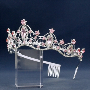 Detailed view of silver bridal crown with pink gemstones and clear rhinestones on acrylic stand