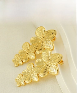 Detail of gold-plated titanium steel earrings featuring three-linked flowers with brushed texture