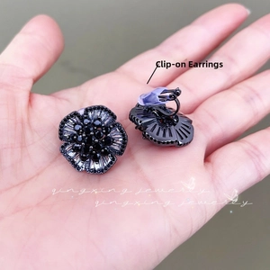 Detail of black camellia flower clip-on earrings with faceted crystals for non-pierced ears