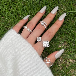 S925 sterling silver ring set with pearl, snake and clover design worn on grass