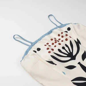 Detailed close-up of floral print and slim blue straps on a white mesh maxi dress