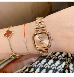 Close-up of elegant rose gold square quartz watch with metal chain strap on woman wrist