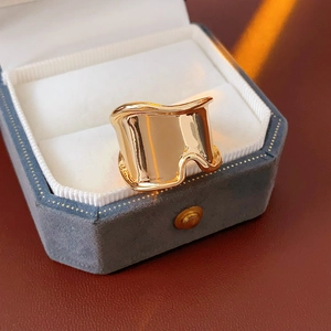 Macro shot of a golden wide wavy ring displayed on a gray velvet jewelry box edge