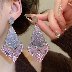 Close-up of bohemian diamond-shaped wooden drop earrings with ethnic geometric patterns