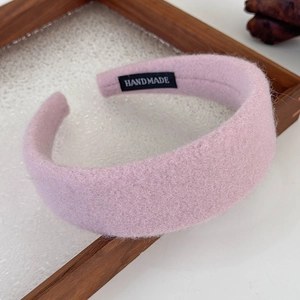 Close-up of handmade pink plush headband featuring soft texture and black handmade label