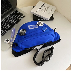 Detail view of royal blue nylon crossbody bag with fashion badges and astronaut pendant