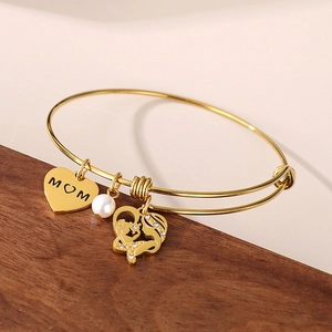 Detail of golden MOM bracelet with heart charms and pearl on a wooden display