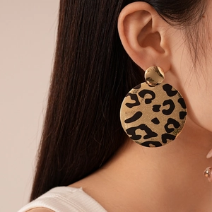 Détail des boucles d'oreilles circulaires à motif léopard doré portées par un mannequin