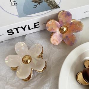 Macro view of floral acetate hair claws in pearl white and amber texture finishes