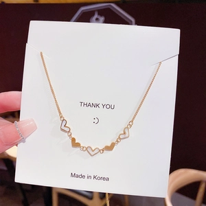 Close-up of gold heart necklace with mother of pearl inlays on a display card