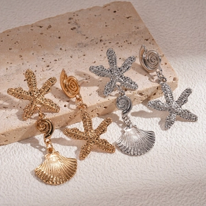 Starfish shell textured dangle earrings in gold and silver finish on travertine stone