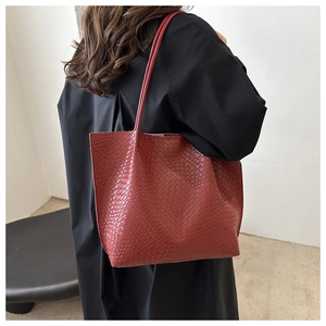 Macro view of red crocodile embossed leather texture on a spacious tote bag