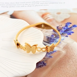 Macro shot of gold butterfly bangle with spring clasp on white shell jewelry tray