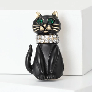 Detailed macro view of black cat brooch with green crystal eyes and rhinestone collar