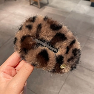 Detailed close-up of a leopard print plush hair clip with a sturdy metal duckbill base