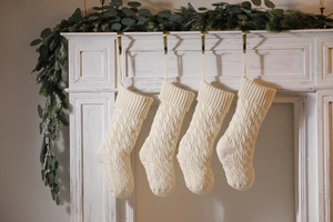 Close-up of cream cable knit Christmas stockings hanging on a festive mantelpiece