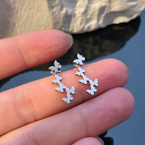 Dettaglio degli orecchini a farfalla in argento con un intricato design geometrico traforato
