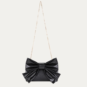 Close-up of black bow-shaped crossbody bag with crocodile texture and gold chain strap